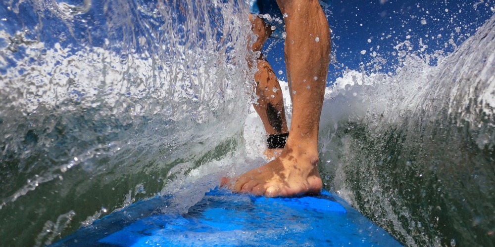Action shot of surfer riding a wave, symbolising resilience and perspective through the famous quote “You can’t stop the waves, but you can learn to surf.”