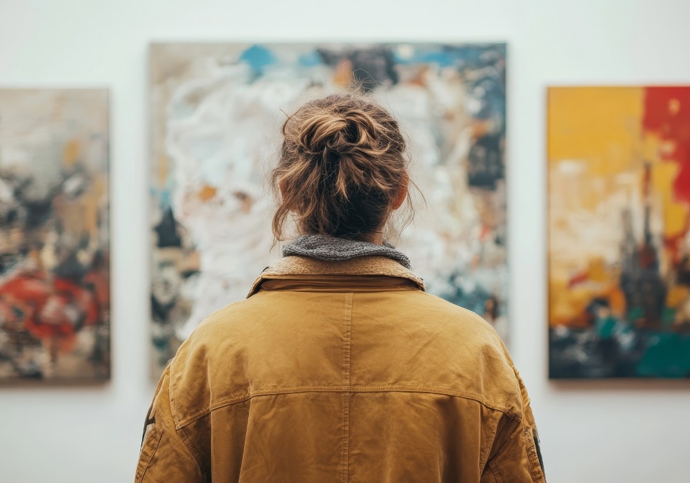 A person viewing colourful abstract paintings in an art gallery symbolising reflection and self-discovery.