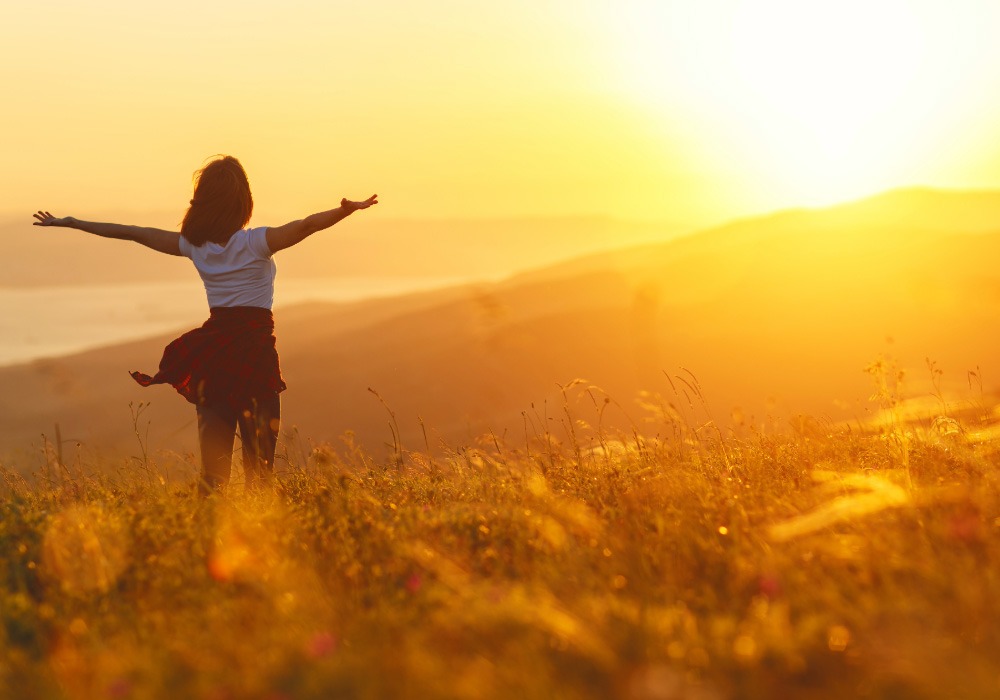 Person standing in sunlight with open arms symbolising awakening and remembering inner wisdom.