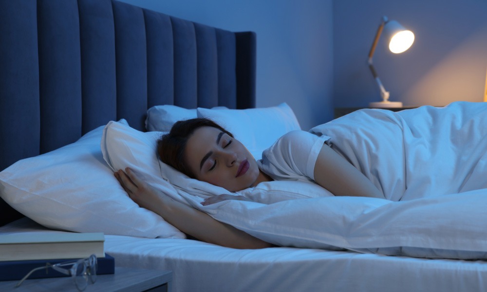 Woman sleeping peacefully in bed at night in a softly lit bedroom.